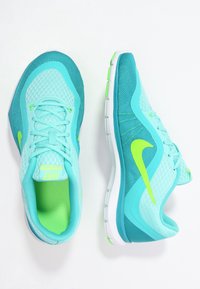 Letvægts løbesko i turkis og grøn med mesh og syntetiske materialer. Har en polstret sål og et kontrastfarvet Nike-logo.