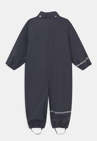 Granatowy wodoodporny kombinezon z długimi rękawami, elastycznymi mankietami i detalami w postaci odblaskowych pasków. Posiada wysoki kołnierz i zatrzaski.
