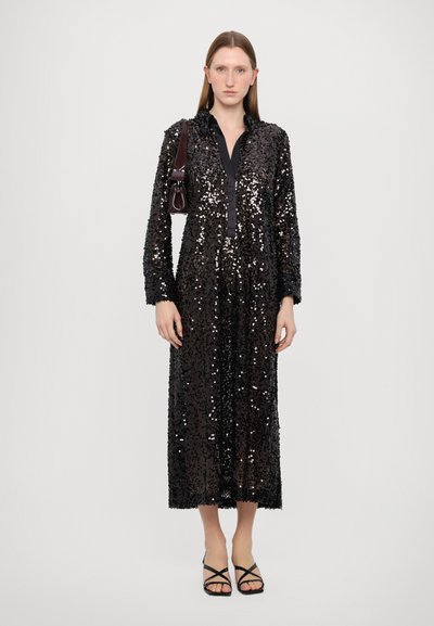 Black sequin long dress with a collared neckline and button closure, featuring long sleeves and a mid-length hem. Paired with black strappy sandals.