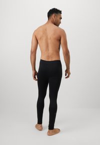 Leggings de sport noirs ajustés avec une texture lisse, une taille haute et des détails minimalistes. Convient pour le sport ou une tenue décontractée.