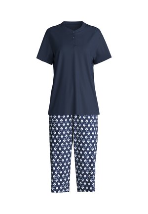 Haut henley à manches courtes bleu marine associé à un pantalon court bleu marine avec un motif floral géométrique blanc.