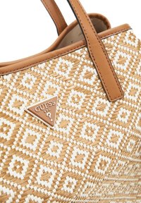 Borsa a tracolla in paglia intrecciata con un motivo geometrico in tonalità beige e bianco, con dettagli in pelle marrone e una placca logo metallica sul davanti.