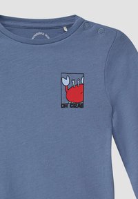 Niebieska koszula z długim rękawem, wykonana z miękkiego materiału, z grafiką czerwonego kraba oraz napisem "DHI CRAB" na czarno, z zatrzaskami na ramieniu.