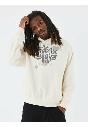 Sudadera color crema con texto gráfico en gris y diseño de corazón en la parte delantera. Hecha de tela suave, presenta un corte relajado y puños elásticos.