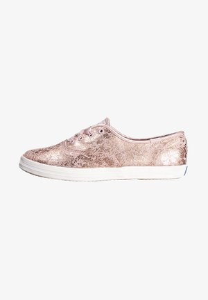 Zapatilla deportiva baja en oro rosa metálico con suela blanca y cordones de satén, vista lateral sobre fondo blanco.