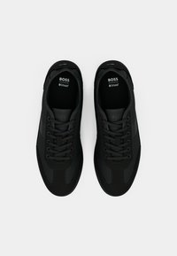 Ζευγάρι μαύρα αθλητικά παπούτσια BOSS με κορδόνια, απεικονιζόμενα από πάνω σε λευκό φόντο.