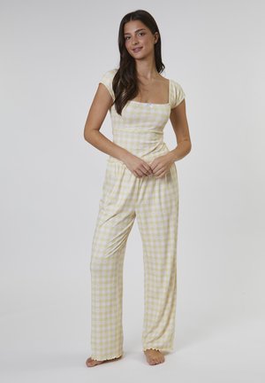 Gult og hvidt ternet pyjamassæt med en tætsiddende kortærmet top og løstsiddende bukser med bølget kant.