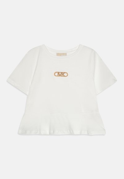 T-shirt blanc à manches courtes avec un ourlet en peplum, présentant un logo de broche de sécurité en ton doré orné de strass à l'avant.