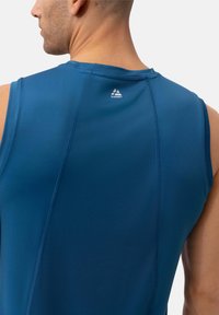 Top sportivo azzurro senza maniche con tessuto testurizzato, caratterizzato da un logo sulla parte posteriore.