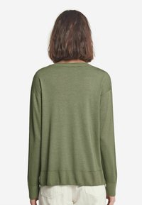 Zielony sweter z dzianiny o luźnym kroju, długich rękawach oraz prążkowanym wykończeniu. Gładka tekstura i szeroki dekolt, przedstawiony z tyłu.