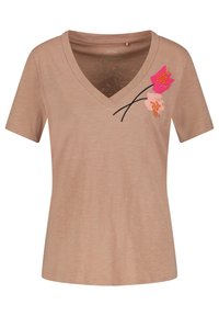 Světle béžové tričko s výstřihem do V vyrobené z měkké látky, s květinovou výšivkou v růžové a oranžové na levé straně. Krátké rukávy, volný střih.