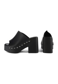 Black platform mules with a smooth, matte finish, featuring silver studs along the side and a chunky block heel. Closed back design.