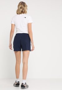 Námořnické šortky s hladkou strukturou, vybavené dvěma zadními kapsami. Nosit s bílým tričkem, na zádech malé logo.