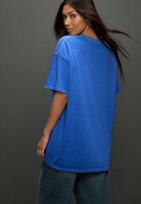 Blauw katoenen t-shirt met een losse pasvorm, korte mouwen en een ronde hals, met een subtiele textuur en een wijde silhouet.