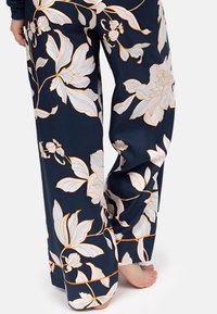 Marineblauwe bloemenbroek met witte en oranje bloemenpatronen, gemaakt van zachte stof, met een losse pasvorm en een wijde pijpdesign.