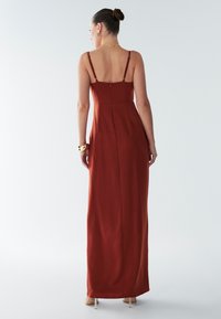 Lång, rostfärgad ärmlös klänning med tunna axelband, sömlös rygg och dragkedjedetalj, tillverkad av slätt tyg med en figurnära silhuett.