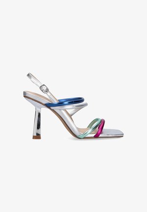Sandalia de tacón aguja plateada con punta cuadrada, que cuenta con tres correas metálicas multicolores en azul, verde y rosa, y un hebilla ajustable en el tobillo.