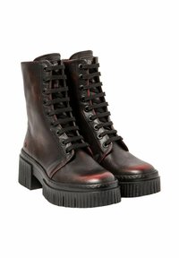 Une paire de bottines en cuir noir à lacets avec des semelles crantées épaisses et des talons blocs, présentées sur un fond blanc.