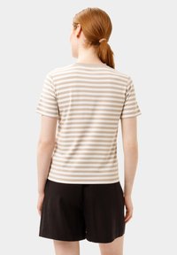 Camiseta de manga corta a rayas en beige y blanco, material de algodón suave, diseño ajustado, costuras planas, combinada con pantalones cortos negros, vista posterior.