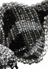 Fekete és ezüst gyöngyökkel díszített tasak, hexagonális gyöngyökkel, amelyek sima textúrával és fényvisszaverő felülettel bírnak, kör alakú nyílásokkal a biztonságos záródás érdekében.