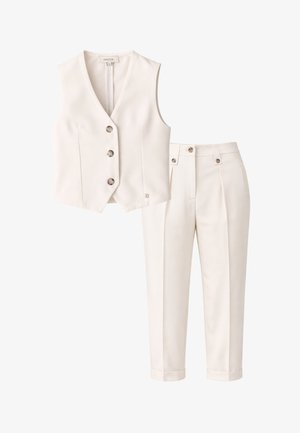 Gilet color crema sartoriale con tre bottoni abbinato a pantaloni abbinati a vita alta con risvolti e dettagli con bottoni.