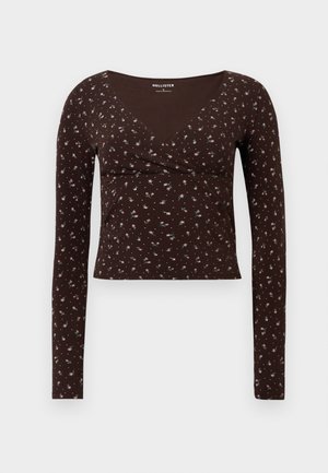 Brown long-sleeve top with a V-neck, featuring a floral pattern in pink and blue. Made of soft fabric with a fitted design.