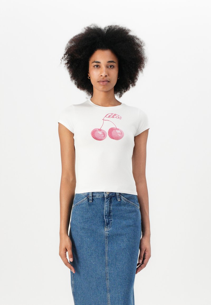 Hvit kortermet t-skjorte med et rosa kirsebærgrafikk og teksten "Guess," kombinert med et blått denim skjørt. Glatt stoff med en tettsittende design.