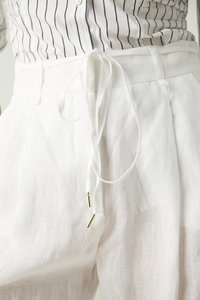 Witte linnen broek met een trekkoord in de tailleband, versierd met gouden accenten. Soepele textuur en een makkelijke val. Gefabriceerd met plooien.