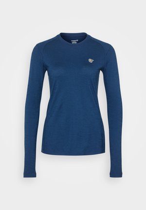 Haut à manches longues en tissu bleu foncé, col rond, design ajusté, avec un petit logo contrastant sur la poitrine gauche. Texture lisse.