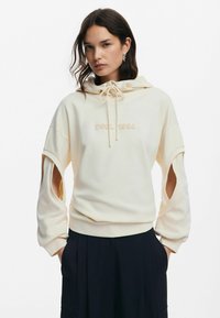 Cream hooded sweatshirt with cut-out sleeves, embellished with "DSL 1984" in matching embroidery. Soft texture, relaxed fit, and drawstring detail.
