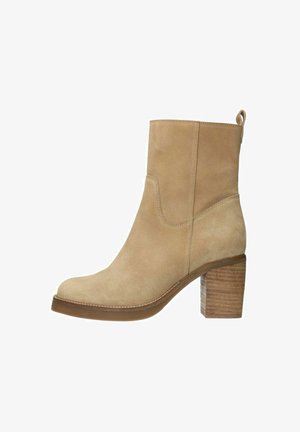 Beige suède enkellaars met een ronde neus en een geprofileerde houten blokhak. Heeft een gestikte rand en een lipje voor gemakkelijke instap.