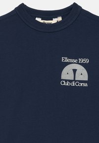 Námořnické bavlněné tričko s kulatým výkrojem a bílou grafikou, na které je na levé části hrudi vytištěno "Ellesse 1959" a "Club di Corsa".