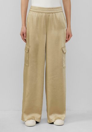 Pantalons cargo en satin beige avec une coupe décontractée, dotés de poches latérales, d'une taille élastique et d'une texture douce et lisse.