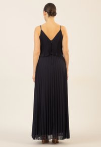 Marineblaues Maxikleid mit Falten, dünnen Trägern und V-Ausschnitt auf der Rückseite. Leichter Stoff fließt bis zu einem durchsichtigen Saum und verfügt über einen diskreten Reißverschluss hinten.