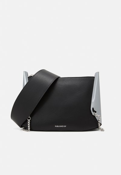 Sort lædertaske med sølv detaljering, lynlåslukning og en aftagelig rem. Har unikke sidelister og kædehardware.