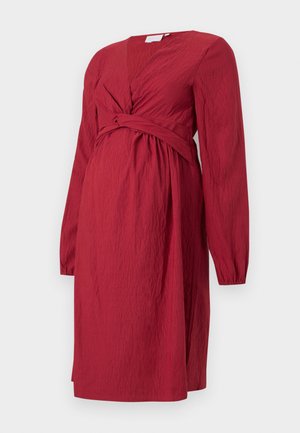 Abito midi rosso con tessuto texturizzato, maniche lunghe, scollatura a V e dettaglio a nodo attorcigliato in vita.