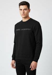 Sudadera negra hecha de una tela suave, con un cuello redondo y puños acanalados, con "KARL LAGERFELD" bordado en color contrastante.