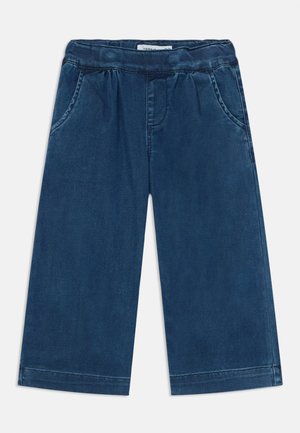 Jeans w ciemnoniebieskim kolorze o szerokich nogawkach, z elastyczną talią, dwoma przednimi kieszeniami i detalami przeszycia wzdłuż nogawek.