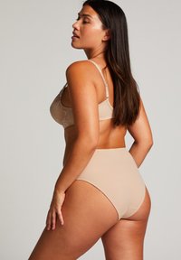 Nude underklädesset som består av en spetsbyst stöd med blomsterbroderi och högmidjade trosor, båda i mjukt, slätt material.