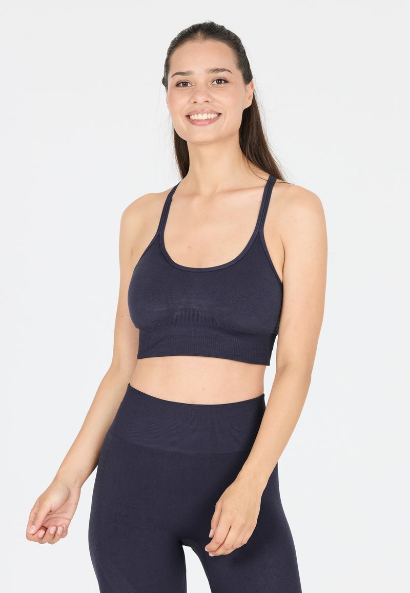 Navyfarbene, verkürzte Sport-BH aus weichem, dehnbarem Stoff. Verfügt über schmale Träger und ein breites Band, kombiniert mit passenden, hoch taillierten Leggings.