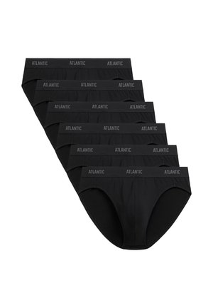 Muskularny mężczyzna o krótkich blond włosach, ubrany w czarne majtki typu slipy z pasem "ATLANTIC", stojący na tle jednolitego jasnego tła.