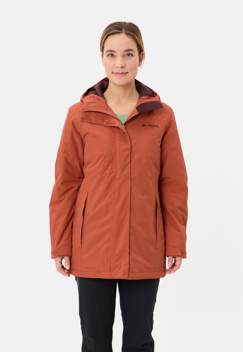 Chaqueta resistente al agua de color óxido, con capucha, bolsillos con cremallera y cierre de cremallera. Presenta un diseño elegante y una textura suave.