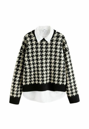 Maglione a pois houndstooth nero e crema con una camicia bianca con colletto sotto. Presenta un design cropped con polsini e orlo a coste.