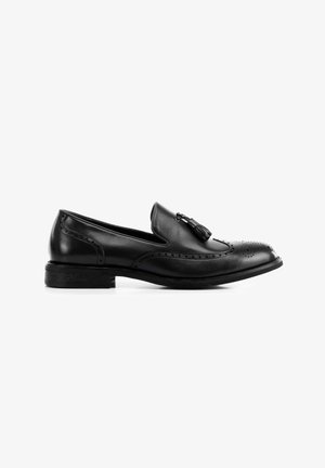 Mocasines de cuero negro con detalle de borlas, perforaciones al estilo brogue y un tacón bajo estratificado. Textura suave con un acabado pulido.