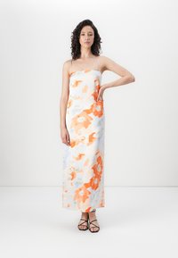 Lång, ärmlös klänning i vitt tyg med orange och blå blommönster. Slimmad passform, rak silhuett, med smala axelband.