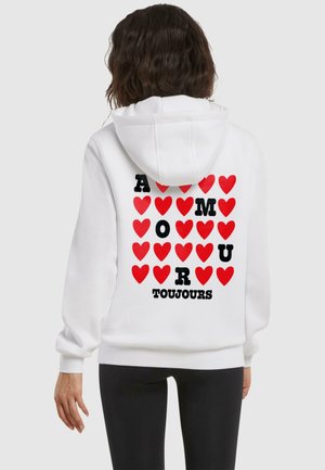 Valge kapuutsiga särk, millel on graafiline kujundus punaste südamega ja must tekst "A M O U R TOUJOURS" seljal. Pehme, mugav kangas.