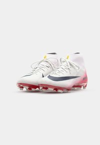 White synthetic soccer cleats with red soles, a textured finish, prominent blue swoosh logo, and yellow accent on the ankle.