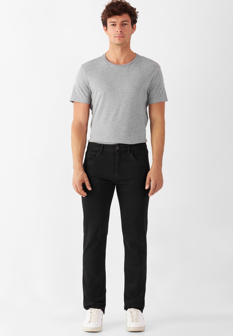 Gray short-sleeve t-shirt paired with black slim-fit jeans and white sneakers. Smooth fabric, casual design, and straight leg shape.