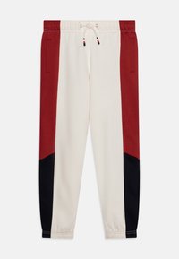 Pantaloni da tuta da uomo con un corpo crema e pannelli laterali neri e rossi, vita elastica con cordino e tasche laterali.