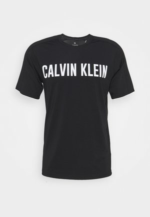 Czarna koszulka z krótkim rękawem z dużym białym napisem "CALVIN KLEIN" na klatce piersiowej i okrągłym dekoltem.
